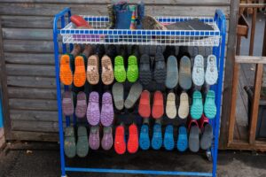 An image of a rack with lots of coloured boots hanging on them.