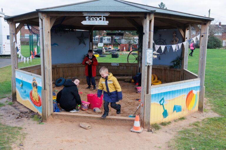 Children playing outside in a sheltered sandpit.