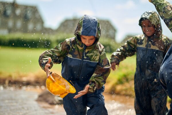 Two children playing in water outdoors at school.