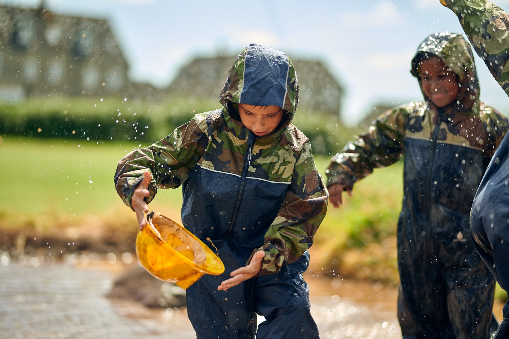 Two children playing in water outdoors at school.